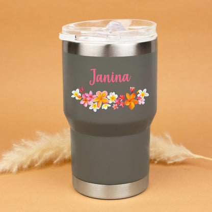 Grauer Thermobecher mit Blumenmotiv und Name Janina personalisiert vor warmem Hintergrund