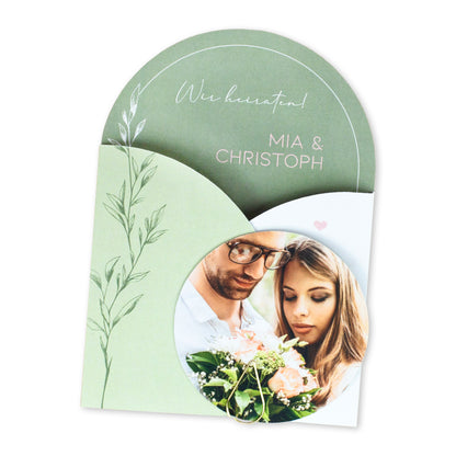 Geschlossene Hochzeitseinladung auf weißem Hintergrund mit rundem Foto, Namen und floraler Gestaltung
