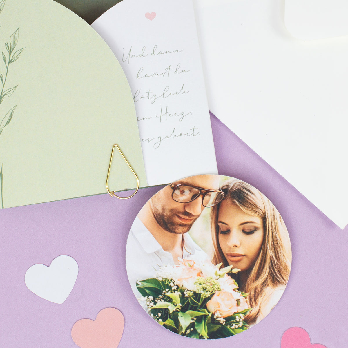 Detailbild der Hochzeitseinladung mit rundem Foto, Umschlag, Herzdeko und goldener Klammer