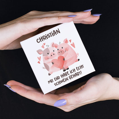 Nahaufnahme des Motivs auf dem Einleger: Zwei niedliche Schweine mit rosa und grauen Flecken sitzen nebeneinander, umgeben von Herzsymbolen. In ihren Hufen halten sie ein großes rotes Herz.