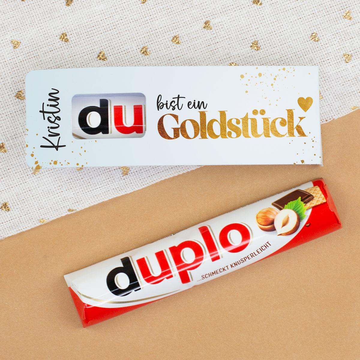 duplo Riegel und Geschenkverpackung mit Goldstück Design auf dekorativem Hintergrund