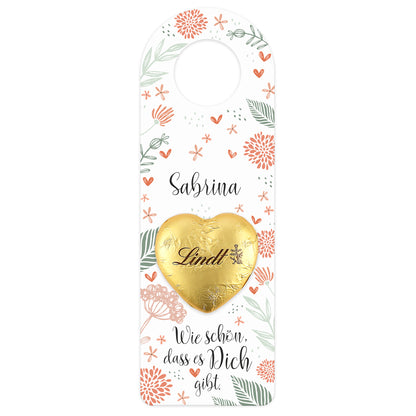Großer Flaschenanhänger mit floraler Gestaltung und Lindt Schokoladenherz – freigestellt auf weißem Hintergrund.