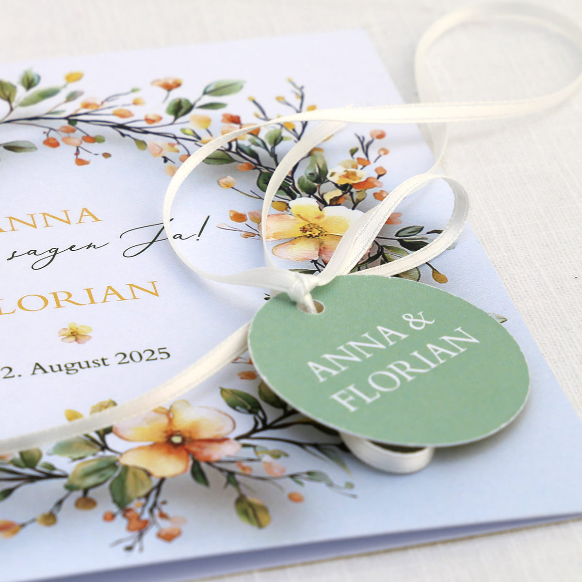 Einladungskarte zur Hochzeit mit Blütenkranz und rundem Anhänger