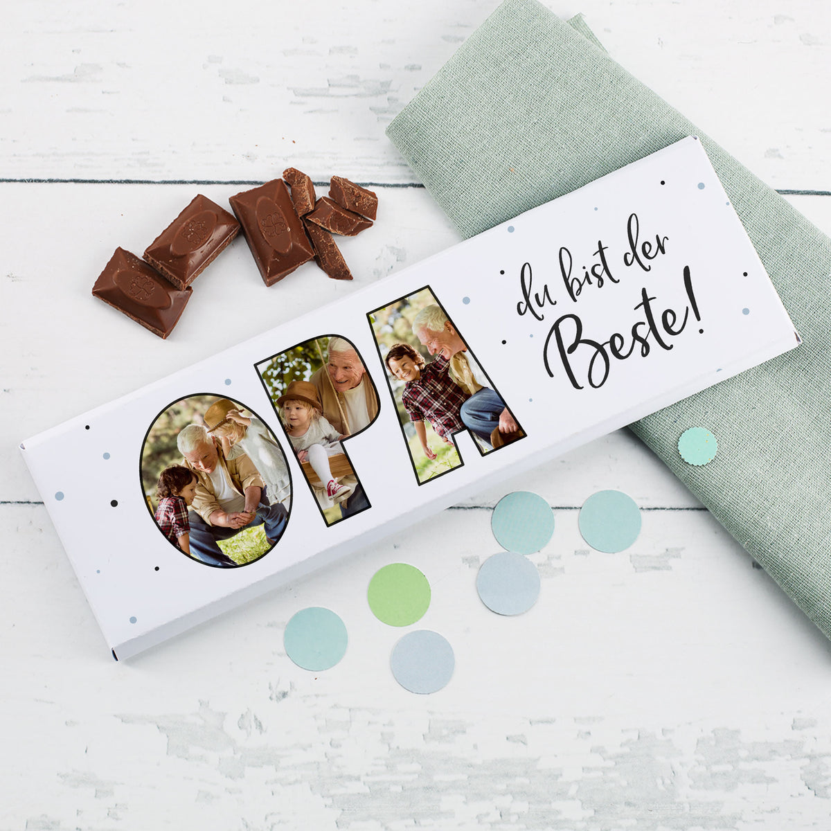 XXL Milchschokolade „Opa du bist der Beste!“ mit personalisierten Bildern, dekorativ auf Holztisch mit Schokolade und Stoffserviette inszeniert