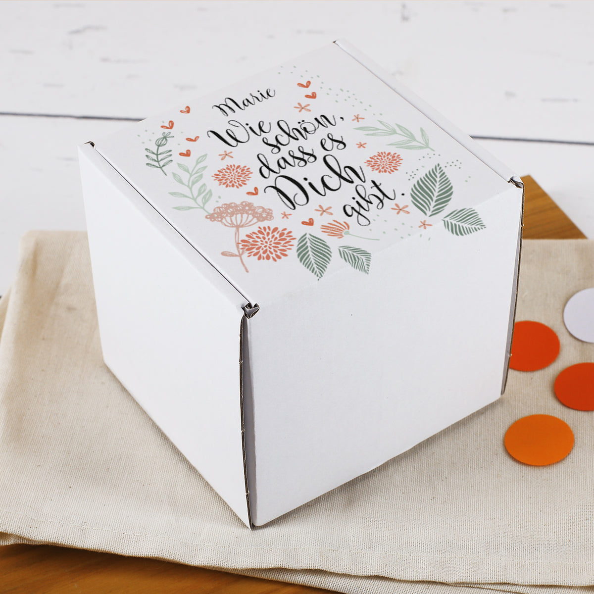 Weiße Geschenkbox mit floralem Design, Schriftzug „Wie schön, dass es dich gibt“ und personalisiertem Namen - geschlossen dargestellt.