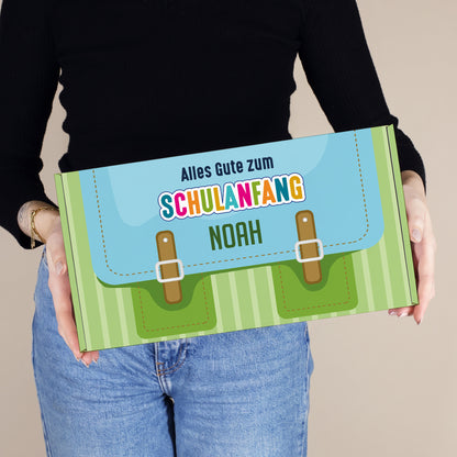 Mittlere personalisierte Geschenkbox zur Einschulung in Grün mit Schulranzen-Design und Wunschname, in den Händen einer Person