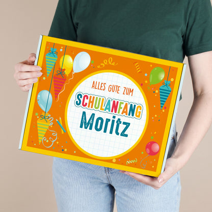 Großer personalisierter Geschenkkarton mit Name und buntem Schulanfang-Motiv, von einer Person gehalten