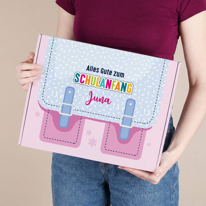 Große personalisierte Pappbox zur Einschulung in Rosa mit Schulranzen-Motiv und Name, von einer Person gehalten