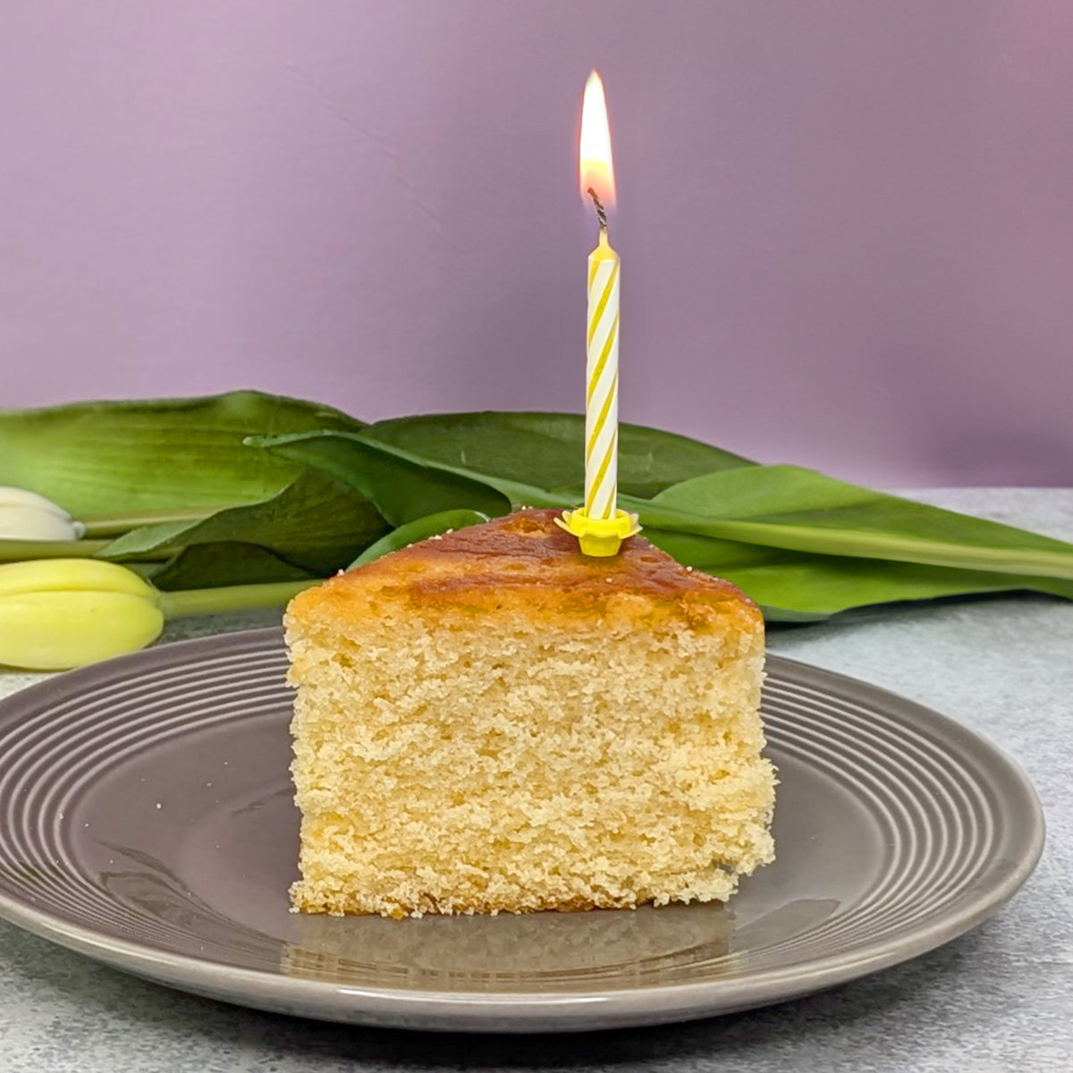 Zitrone Kuchenstück mit Kerze - angerichtet auf einem Tisch