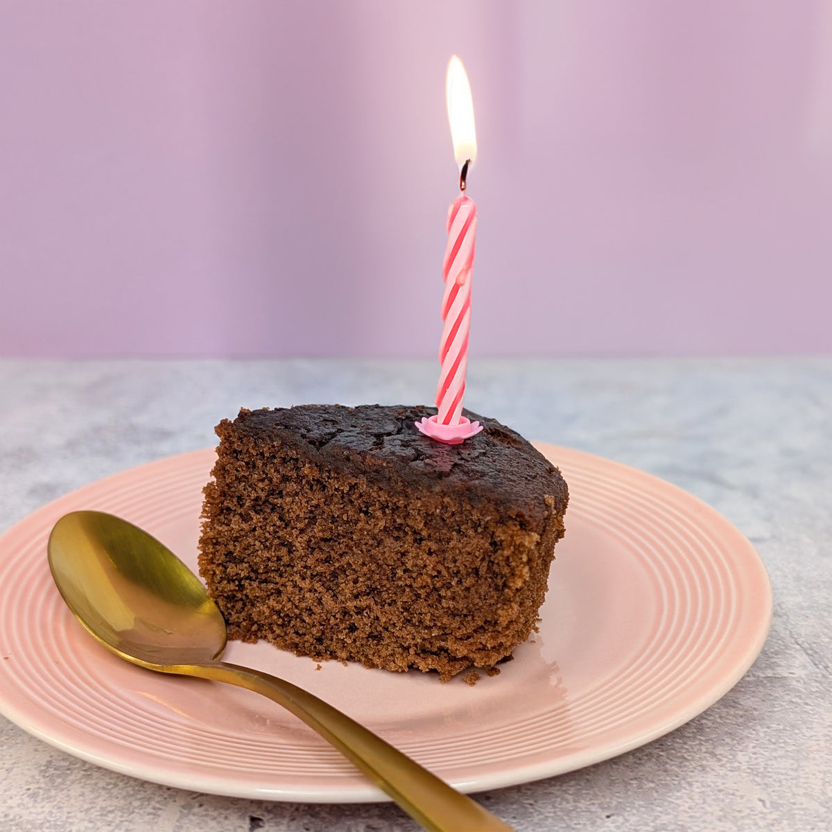 Schoko Kuchenstück mit Kerze - angerichtet auf einem Tisch