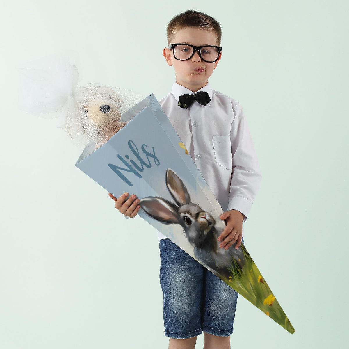 Kind mit personalisierter Schultüte mit Hasenmotiv und dem Namen „Nils“