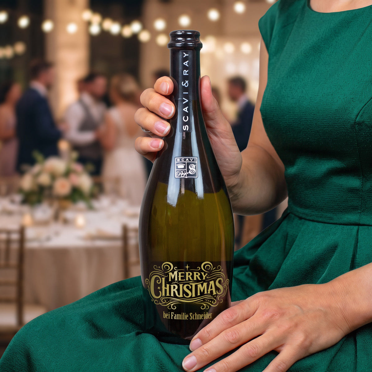 Person hält personalisierten Scavi & Ray Prosecco mit goldfarbenem Merry-Christmas-Motiv und Weihnachtsgruß bei einer festlichen Feier
