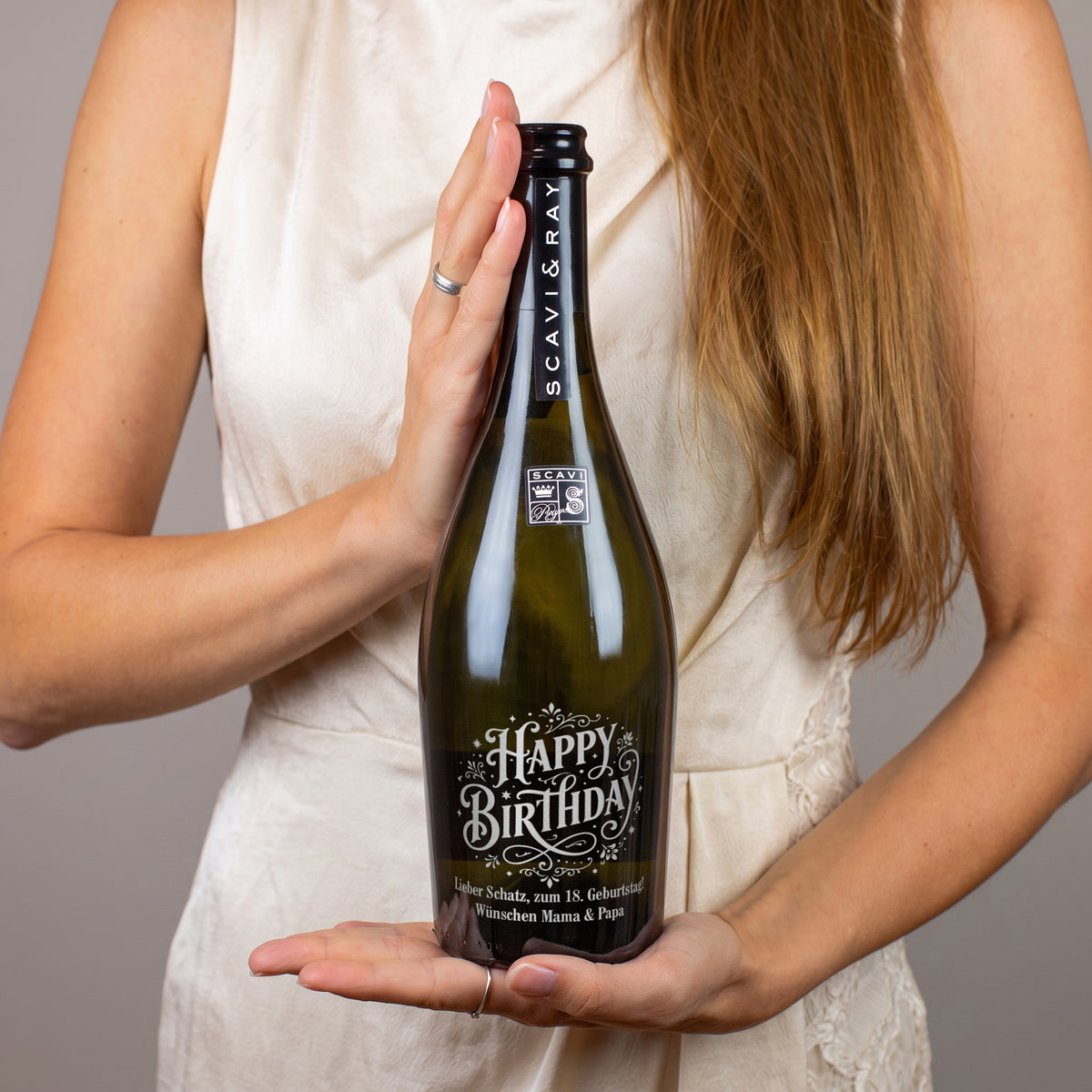Person hält personalisierte Scavi & Ray Prosecco-Flasche mit Happy-Birthday-Gravur und Geburtstagsgruß zum 18. Geburtstag von Mama und Papa