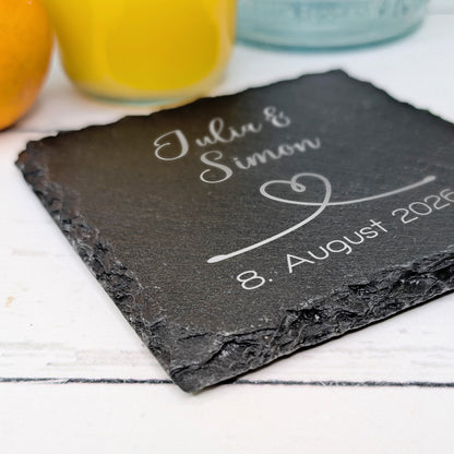 Graviertes Schiefer-Untersetzer-Geschenk mit Herzmotiv und Datum, perspektivische Nahaufnahme mit Namen "Julia & Simon"