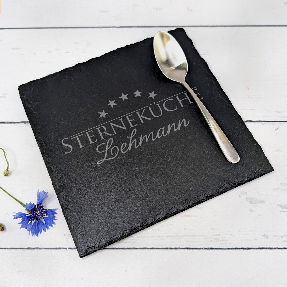 Gravierte Platte auf Tisch mit Löffel und Blume