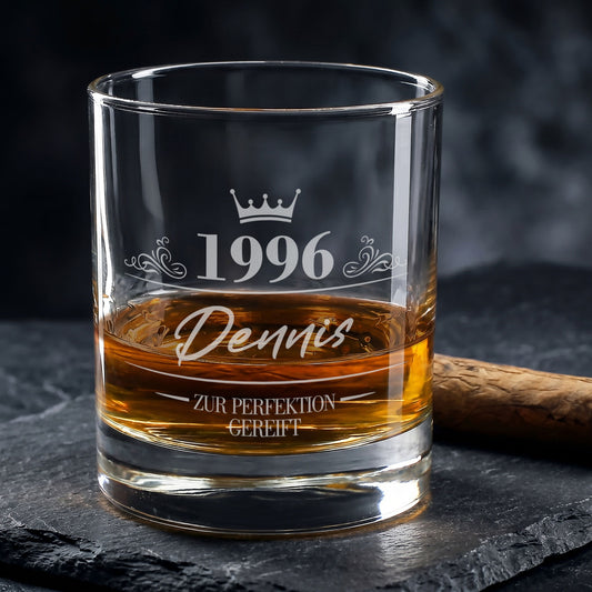 Personalisiertes Whiskyglas zum Geburtstag mit Gravur von 1996, Name Dennis und Krone, gefüllt mit Whisky neben Zigarre