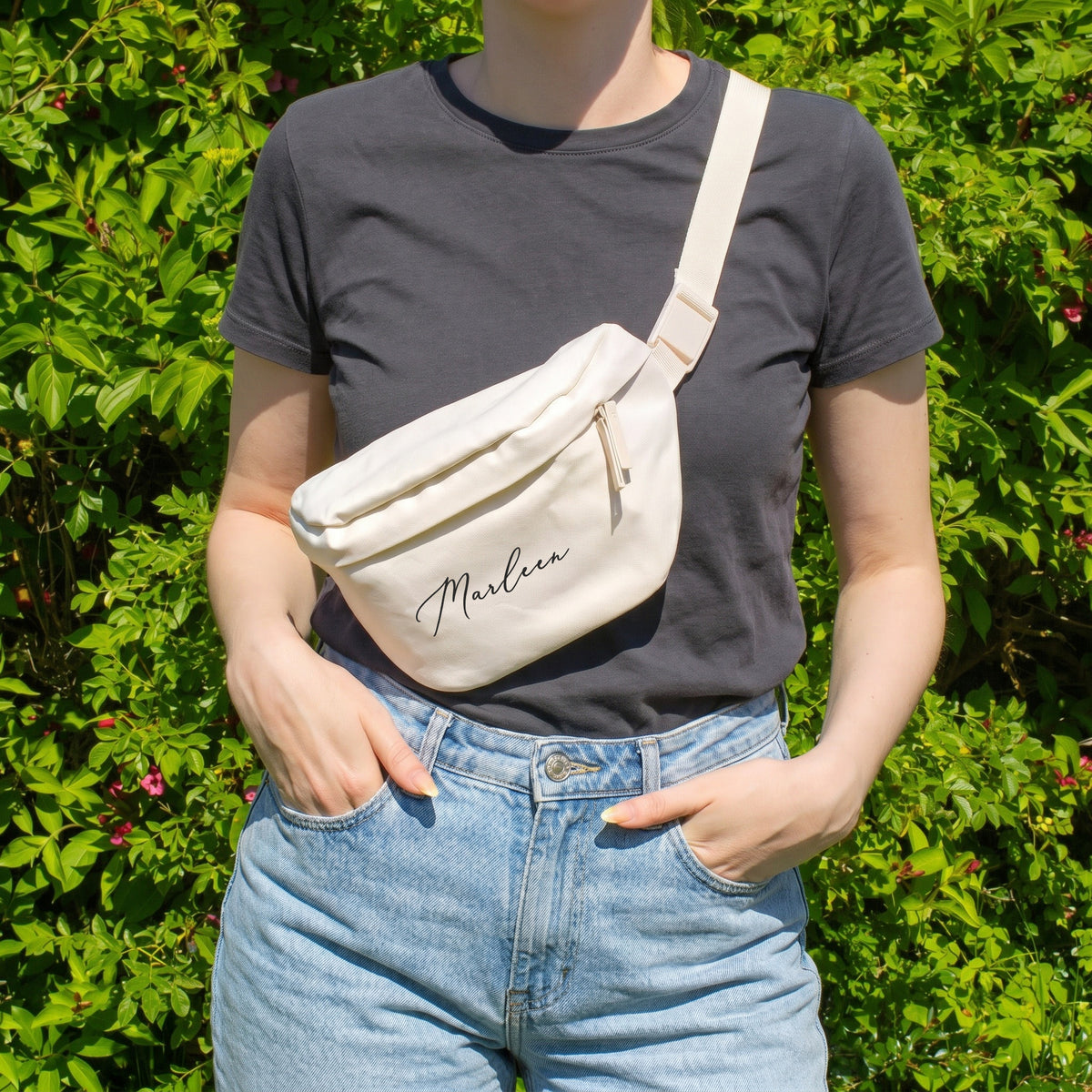 Cremefarbene Bauchtasche mit Name Marleen als Crossbody Bag getragen vor grünem Hintergrund