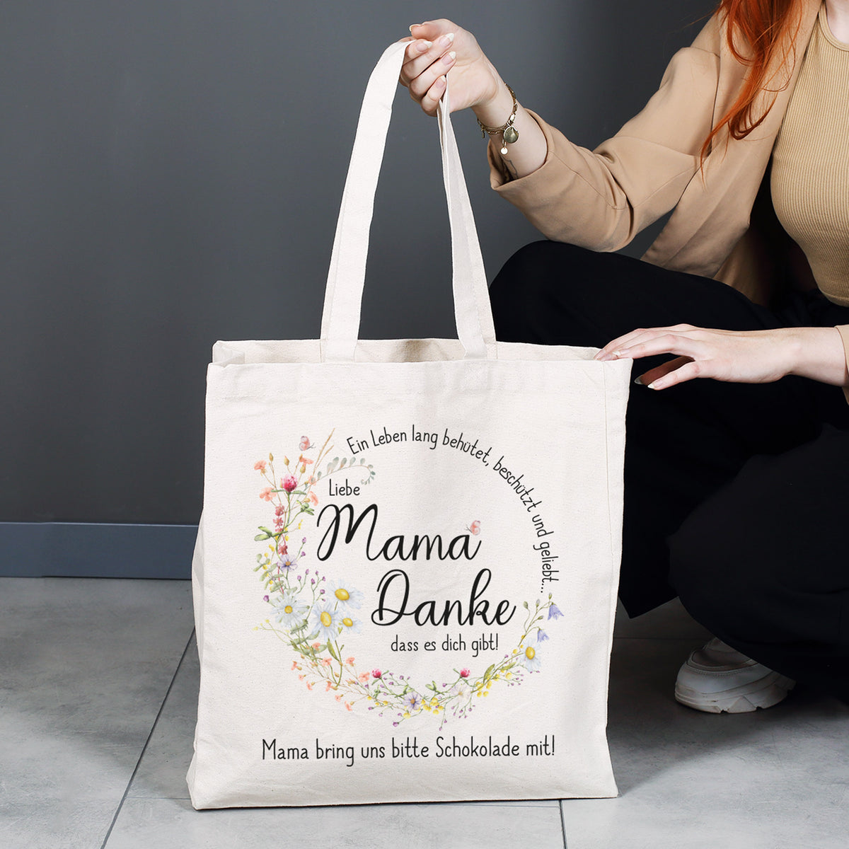Großer Baumwollbeutel für den Alltag – Shopper mit liebevollem Mama-Spruch und floralem Design, gehalten von einer Person, ideal für Einkäufe und Besorgungen.