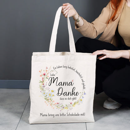 Großer Baumwollbeutel für den Alltag – Shopper mit liebevollem Mama-Spruch und floralem Design, gehalten von einer Person, ideal für Einkäufe und Besorgungen.