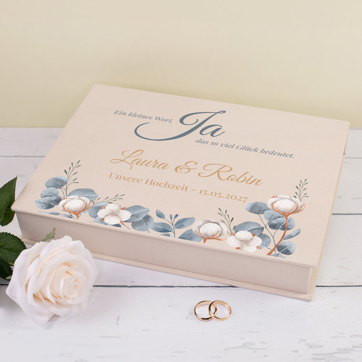 Beige Erinnerungsbox in Buchform zur Hochzeit mit Namen, Datum, Eukalyptus-Design und dekorativen Eheringen