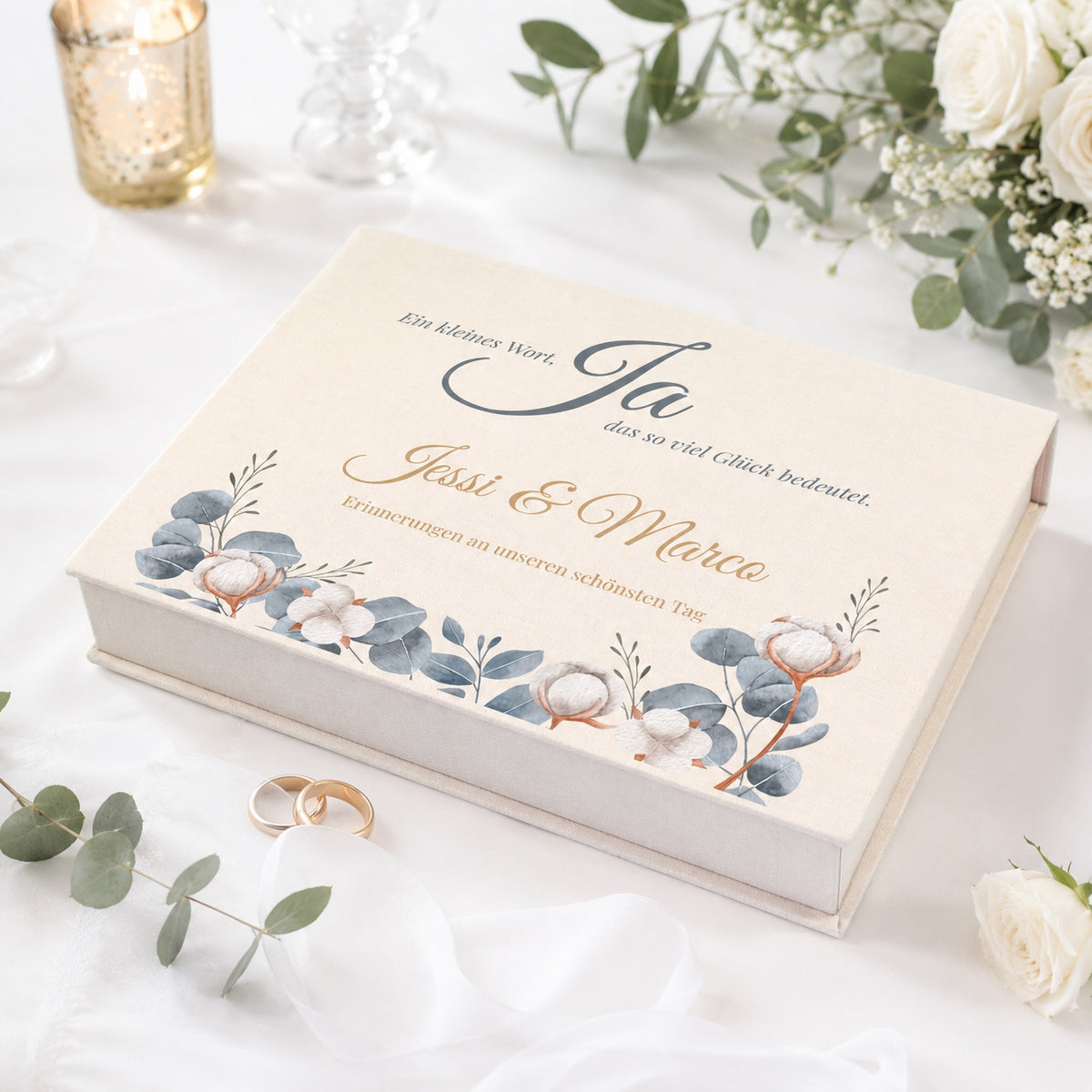Personalisierte Erinnerungsbox zur Hochzeit mit Eukalyptus-Motiv, Baumwollblüten, Namen und Wunschtext auf festlich gedecktem Tisch