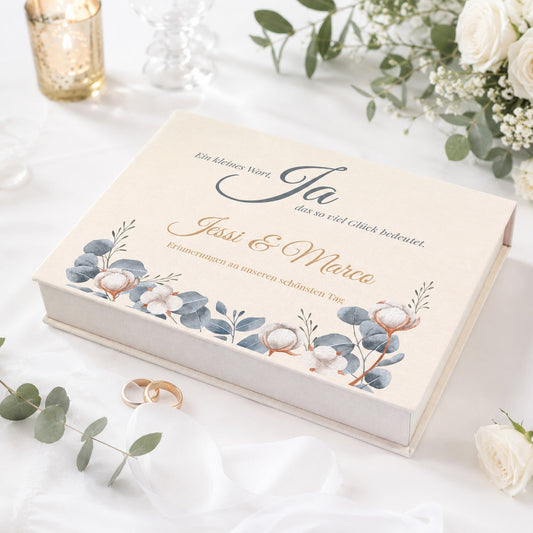 Personalisierte Erinnerungsbox zur Hochzeit mit Eukalyptus-Motiv, Baumwollblüten, Namen und Wunschtext auf festlich gedecktem Tisch