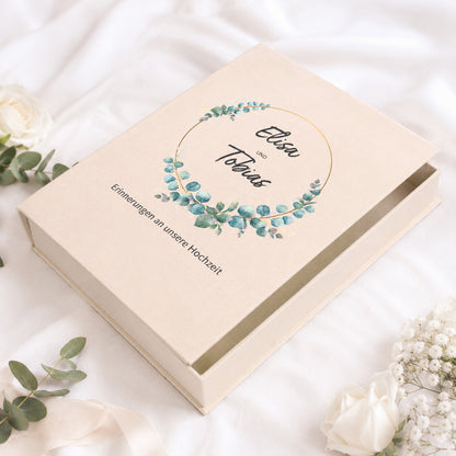 Personalisierte Erinnerungsbox zur Hochzeit mit Eukalyptus-Kranz, Namen und Wunschtext auf hellem Stoff dekoriert