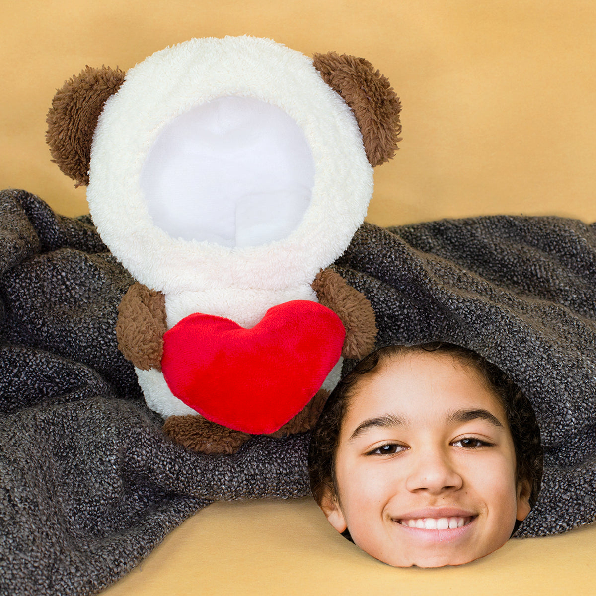 Kuscheltier Teddy mit rotem Herz und personalisiertem Foto-Gesicht auf grauer Decke