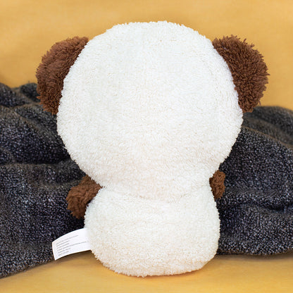 Rückansicht des cremeweißen Teddy-Kuscheltieres mit braunen Ohren auf grauer Decke