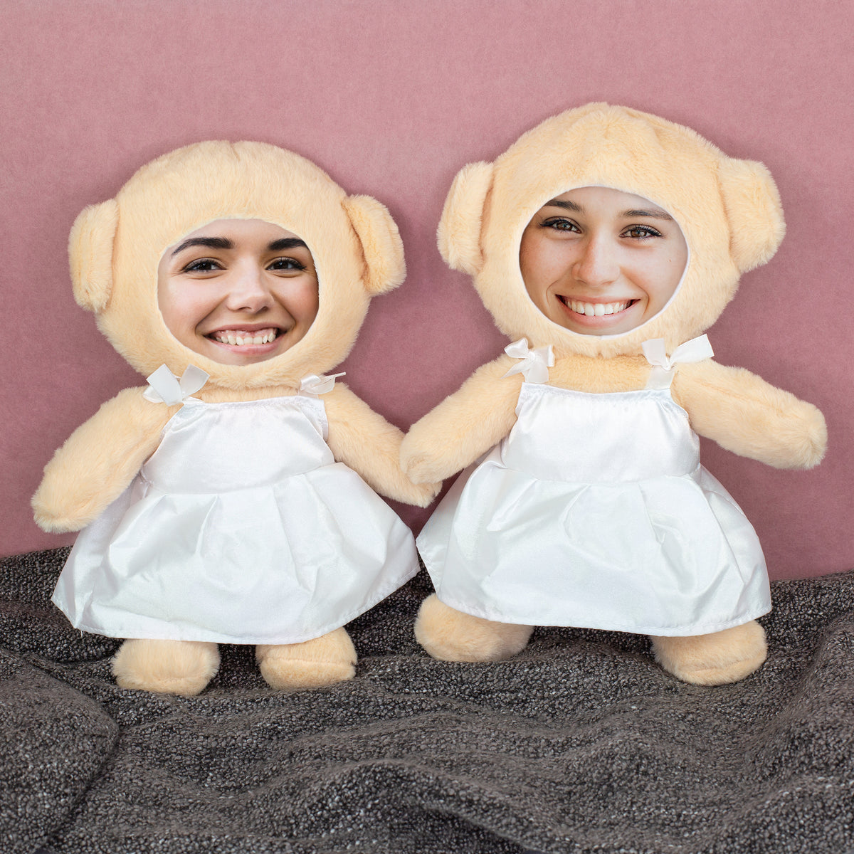 Zwei personalisierte Braut-Teddys mit Foto-Gesichtern auf grauer Decke vor rosa Hintergrund