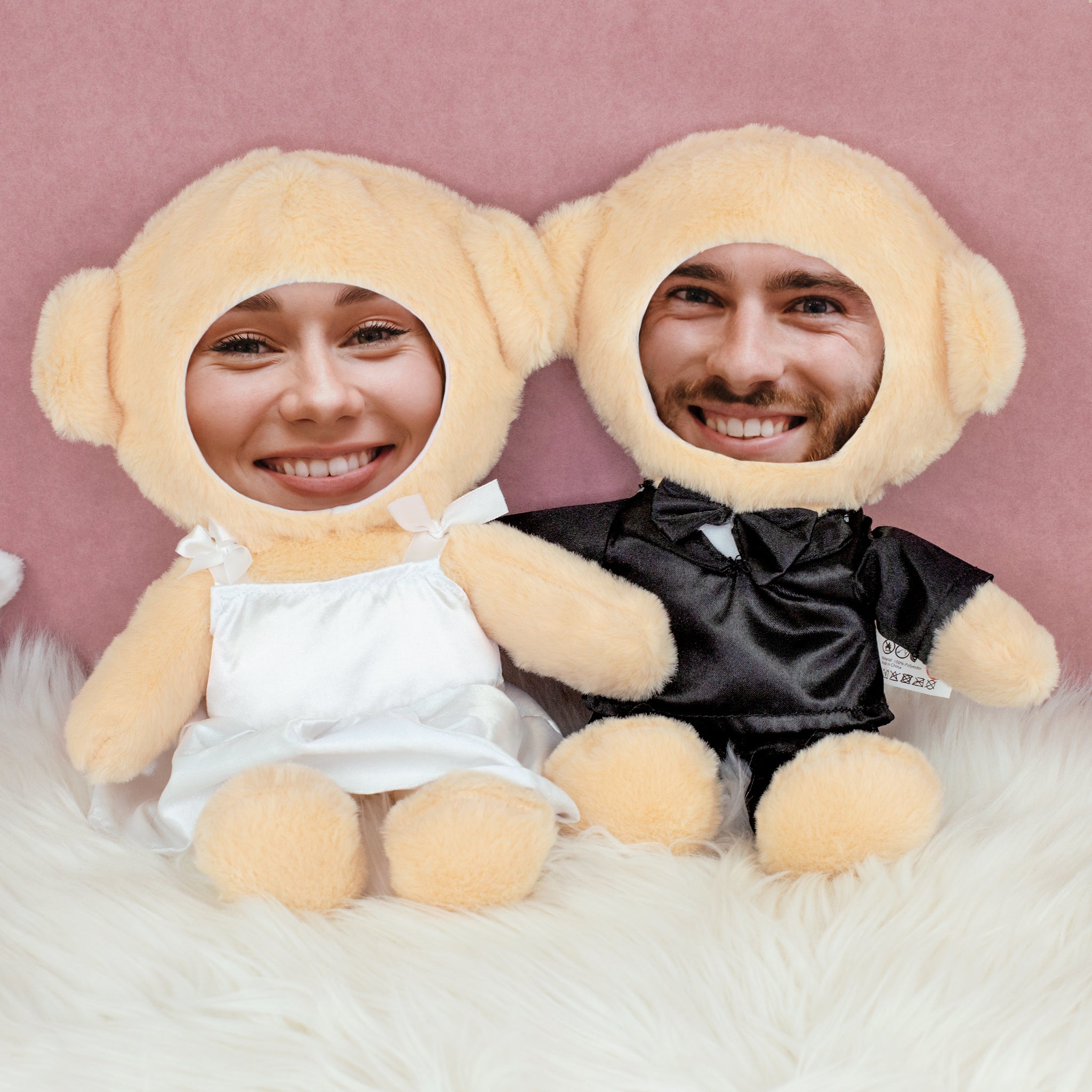 Teddy Brautpaar mit eigenen Fotogesichtern sitzend auf weißem Fell vor rosa Hintergrund