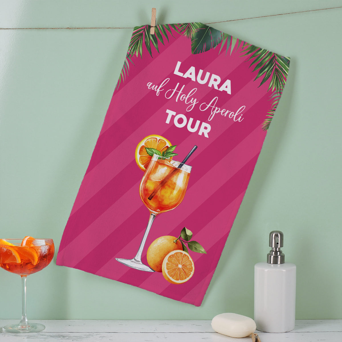 Aufgehängtes Gästehandtuch mit Aperol-Motiv und personalisiertem Text – kompakte, dekorative Präsentation.