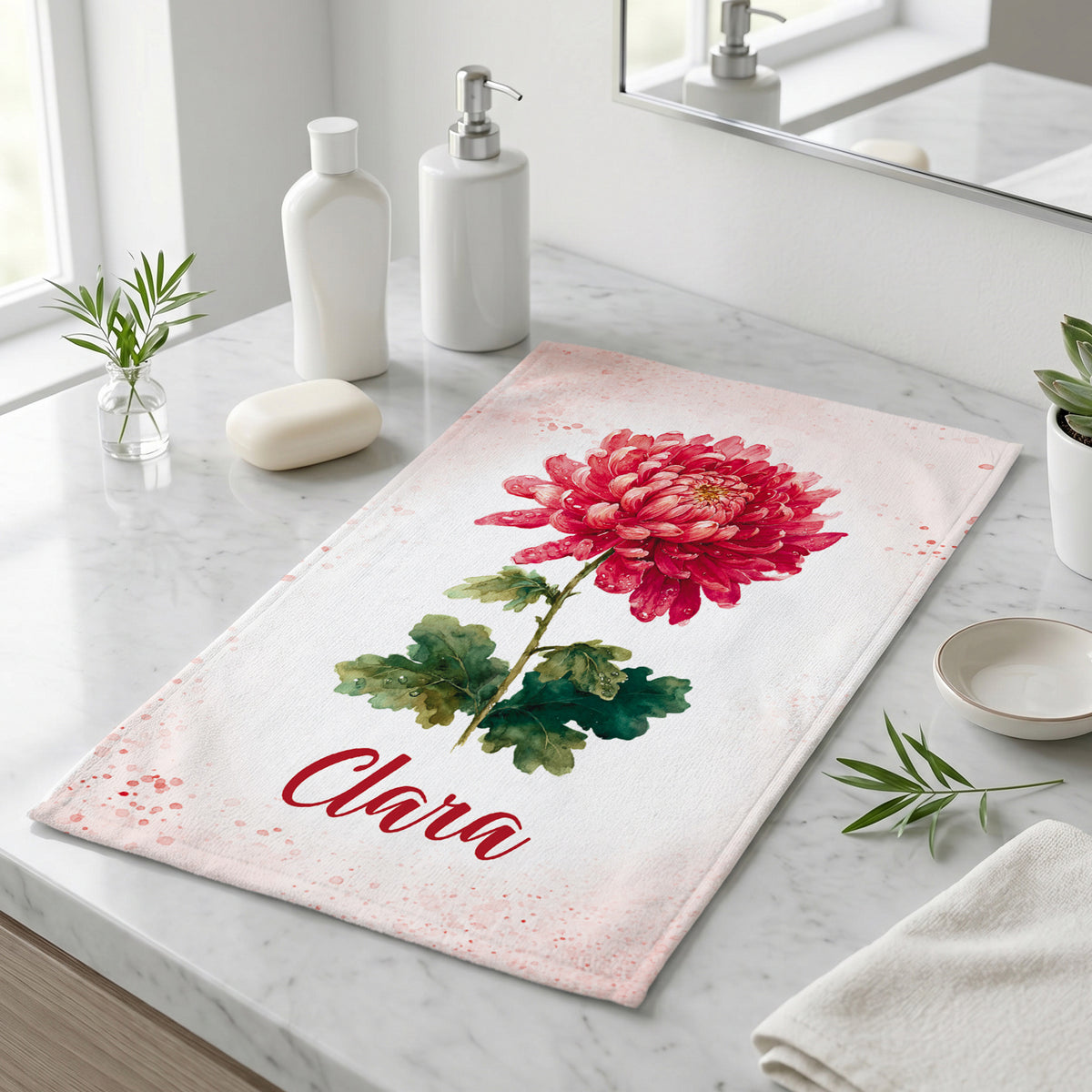 Handtuch mit roter Chrysantheme als Geburtsblume und Name Clara auf Marmorfläche