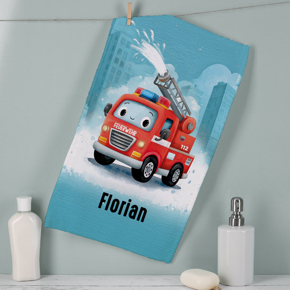 Feuerwehr Handtuch mit Name Florian, rotem Feuerwehrauto und 112 Motiv im Badezimmer aufgehängt
