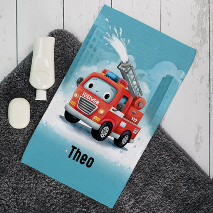 Personalisiertes Kinderhandtuch mit Feuerwehrauto Motiv und Name Theo auf grauem Badteppich