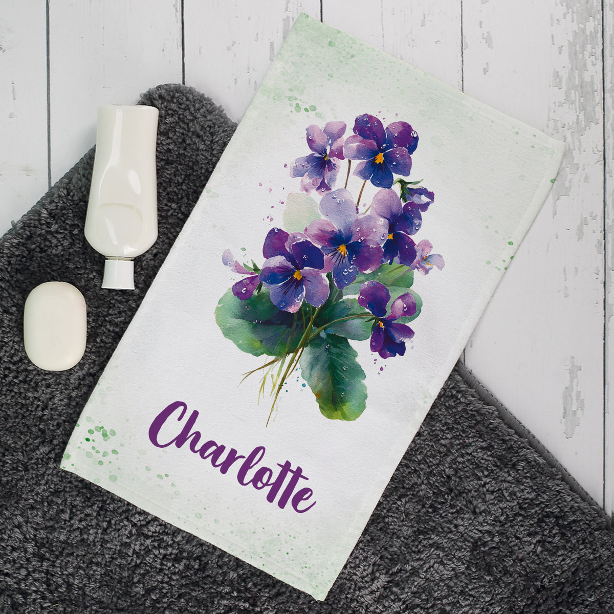 Gästehandtuch mit violettem Veilchen-Motiv und Name Charlotte im Badezimmer