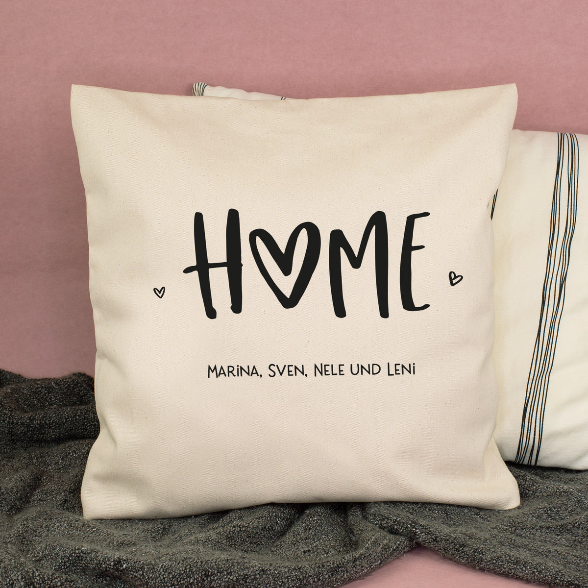Naturfarbenes HOME Kissen mit Wunschtext Marina Sven Nele und Leni auf dem Sofa