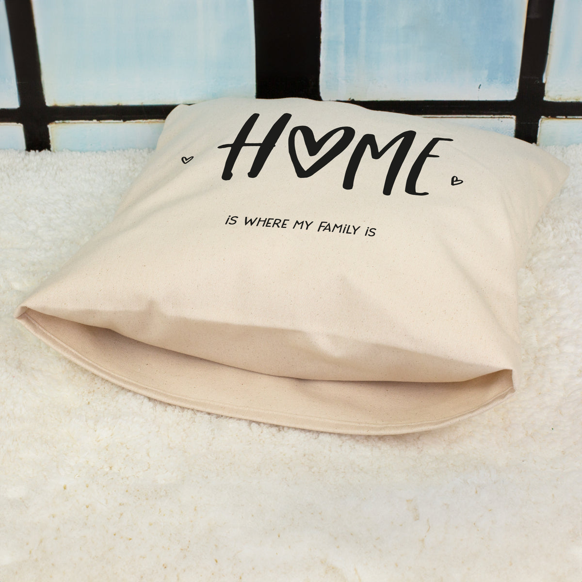 Natur Kissen mit HOME Motiv und Spruch Home is where my family is liegend auf Fell