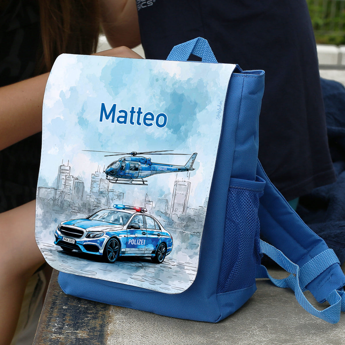 Personalisierter Kindergartenrucksack mit Name Matteo und Polizeiauto-Motiv auf einer Bank