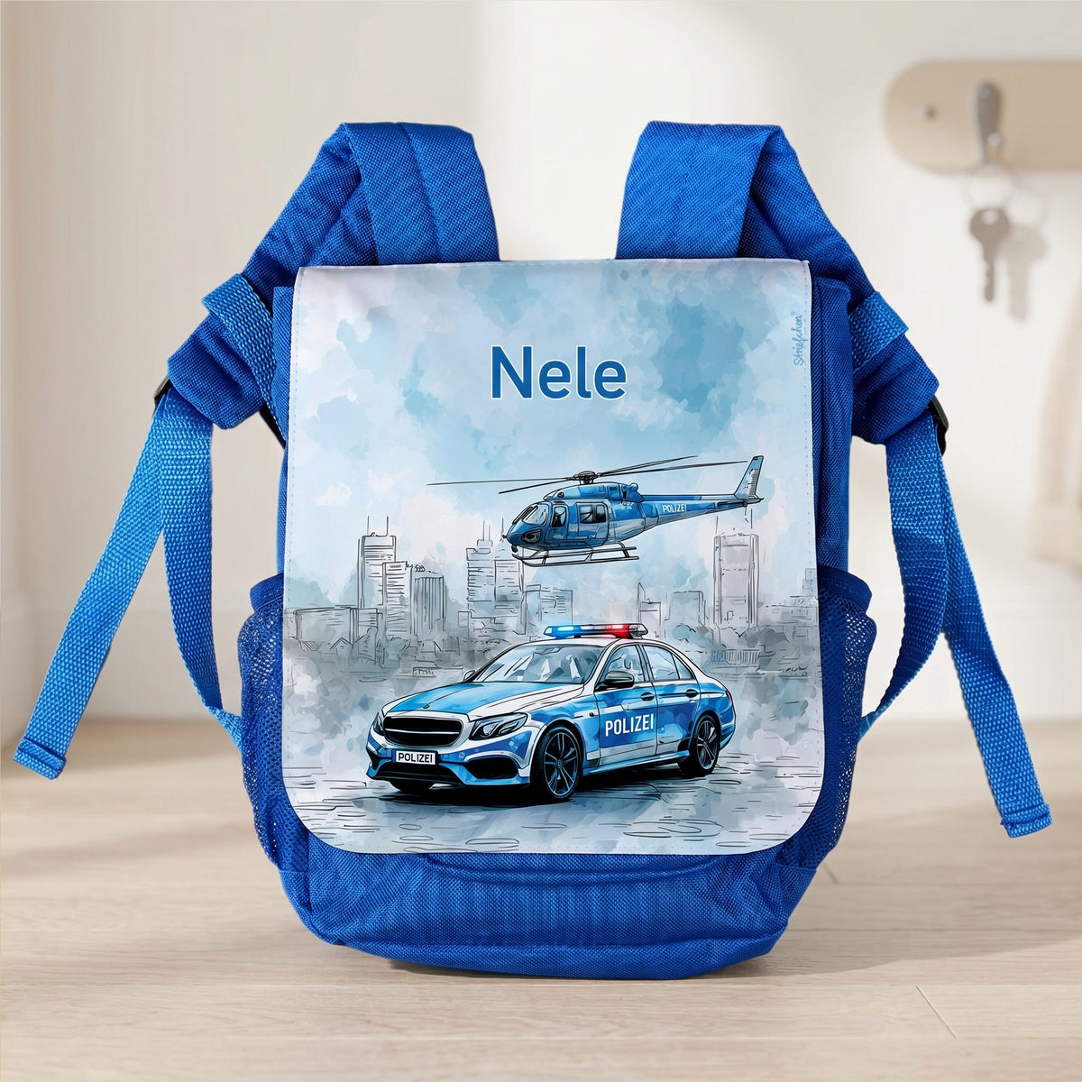 Blauer Kindergartenrucksack mit Name Nele und Polizei-Motiv im Flur vor heller Wand