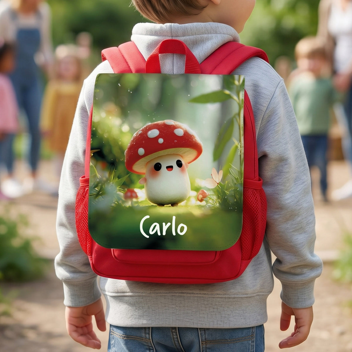 Roter Kindergartenrucksack mit Name Carlo und Glückspilz-Motiv auf dem Rücken eines Kindes im Freien