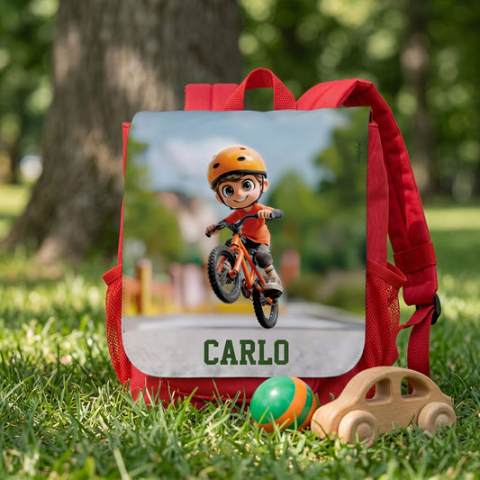 Personalisierter Jungenrucksack mit Fahrrad-Motiv und Name Carlo im Gras mit Holzspielzeug