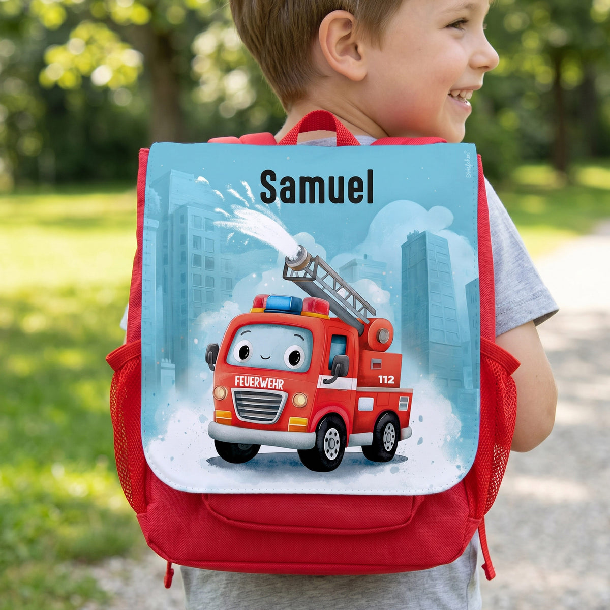 Kind trägt roten Kindergartenrucksack mit Feuerwehr-Motiv, Wasserspritze und Name Samuel auf der Frontlasche