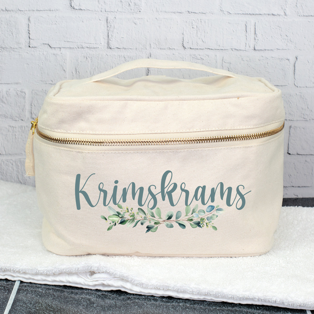 Personalisierter Kulturbeutel mit Aufdruck Krimskrams und Eukalyptus-Motiv auf einem Handtuch
