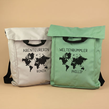 Zwei 2-in-1 Rucksäcke in Beige und Mintgrün mit Weltkarten-Motiv sowie personalisiertem Wunschtext und Namen vor hellem Hintergrund