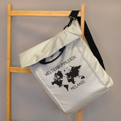 Beiger 2-in-1 Rucksack mit Weltkarten-Motiv, Wunschtext „Weltenbummlerin“ und Name „Melanie“ an einer Holzleiter aufgehängt