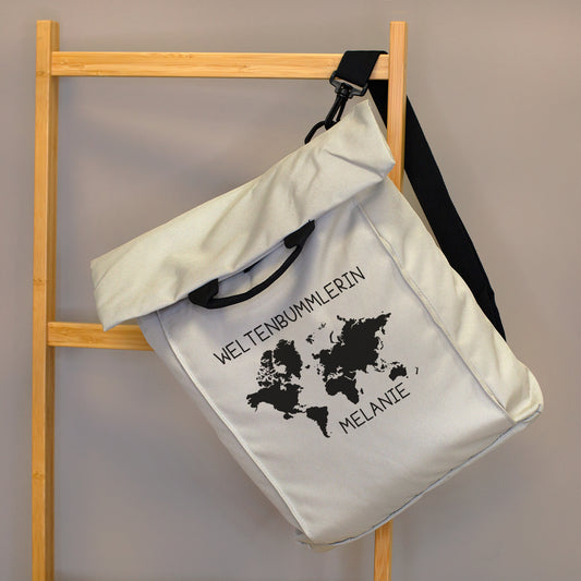 Beiger 2-in-1 Rucksack mit Weltkarten-Motiv, Wunschtext „Weltenbummlerin“ und Name „Melanie“ an einer Holzleiter aufgehängt