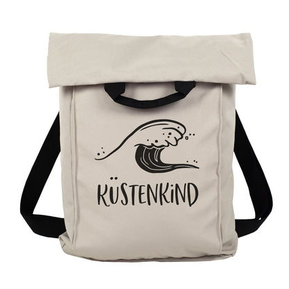Beiger 2-in-1 Rucksack mit Wellenmotiv und Wunschtext Küstenkind vor weißem Hintergrund