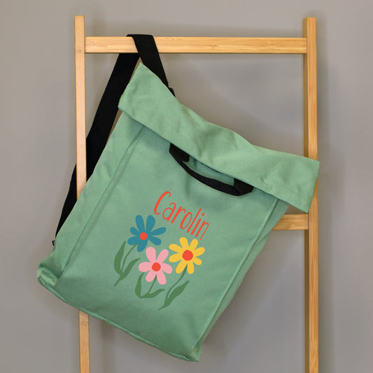 Jadegrüner 2-in-1 Rucksack mit Blumenmotiv und Name Caroline, seitlich an einer Holzleiter hängend