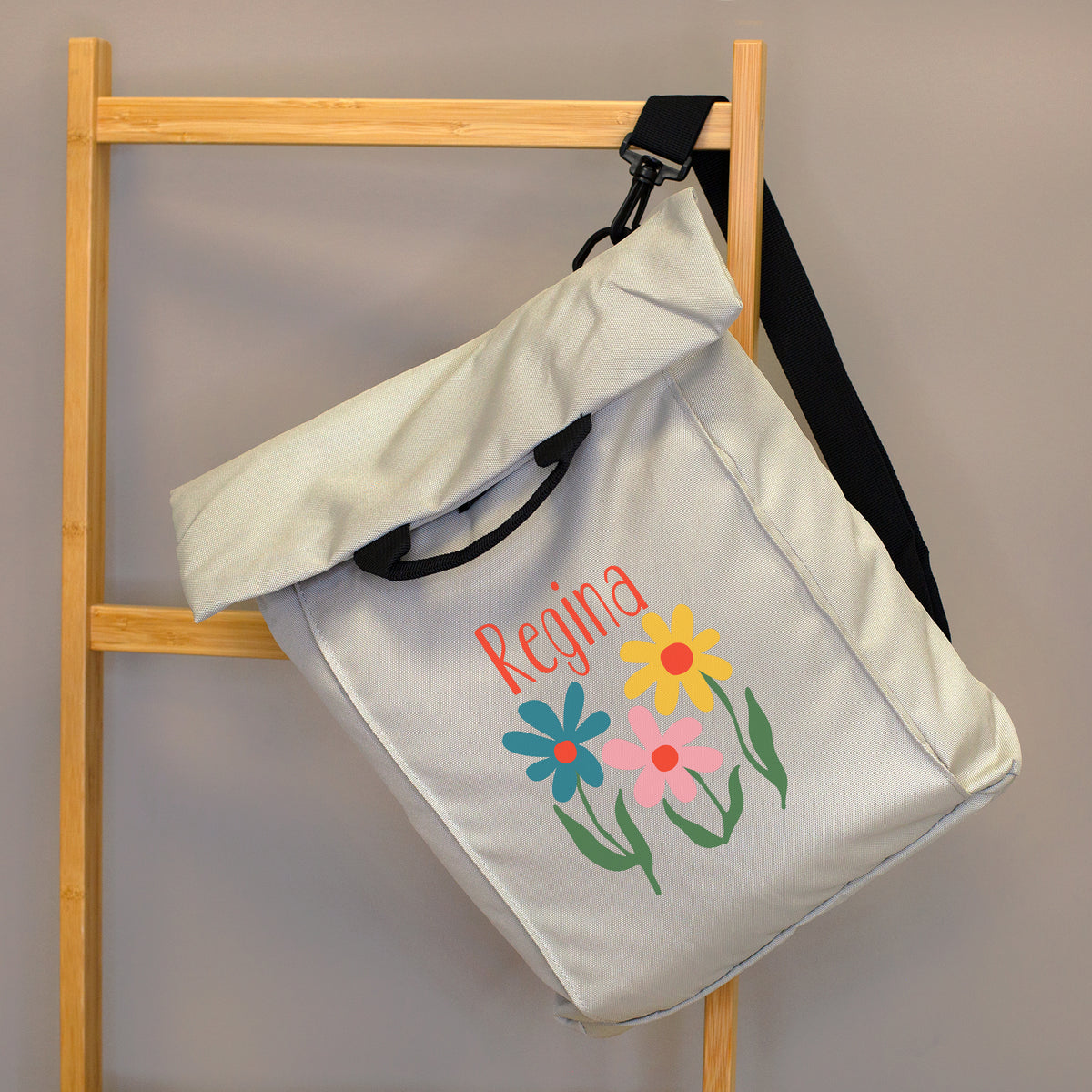 Beiger 2-in-1 Rucksack mit Blumenmotiv und Name Regina, seitlich an einer Holzleiter präsentiert